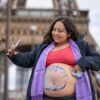Femme enceinte avec un bellypainting prenant un selfie devant la tour eiffel