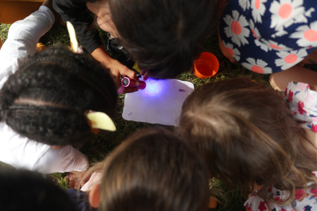 Cinq enfants observent un message secret à l'aide d'une lampe à lumière violette lors d'un anniversaire "licornes" à domicile à Lorient