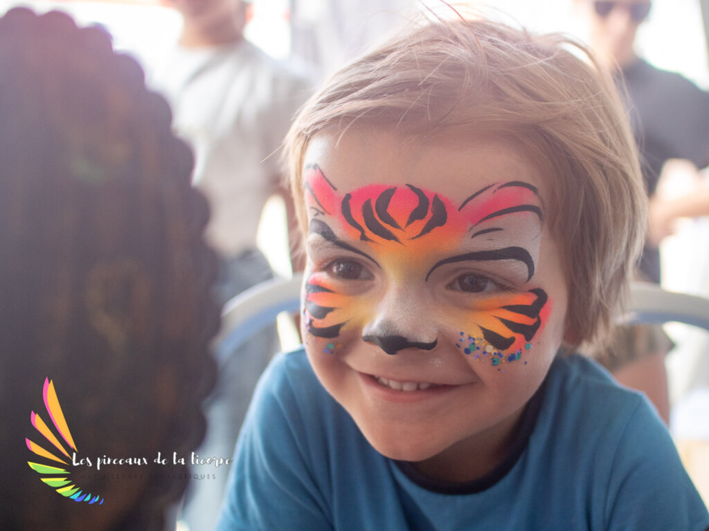 Photo d'un enfant avec un maquillage de tigre fluo qui se regarde dans le miroir